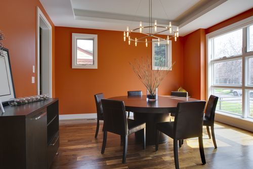 Sophisticated dining room setup with chocolate brown dining table and orange wall paint