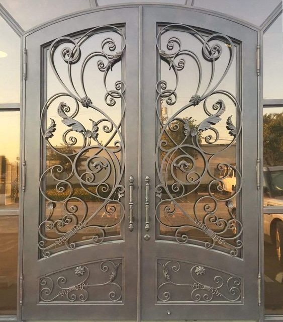 Wrought iron modern gate design against a glass plate with intricate detailing