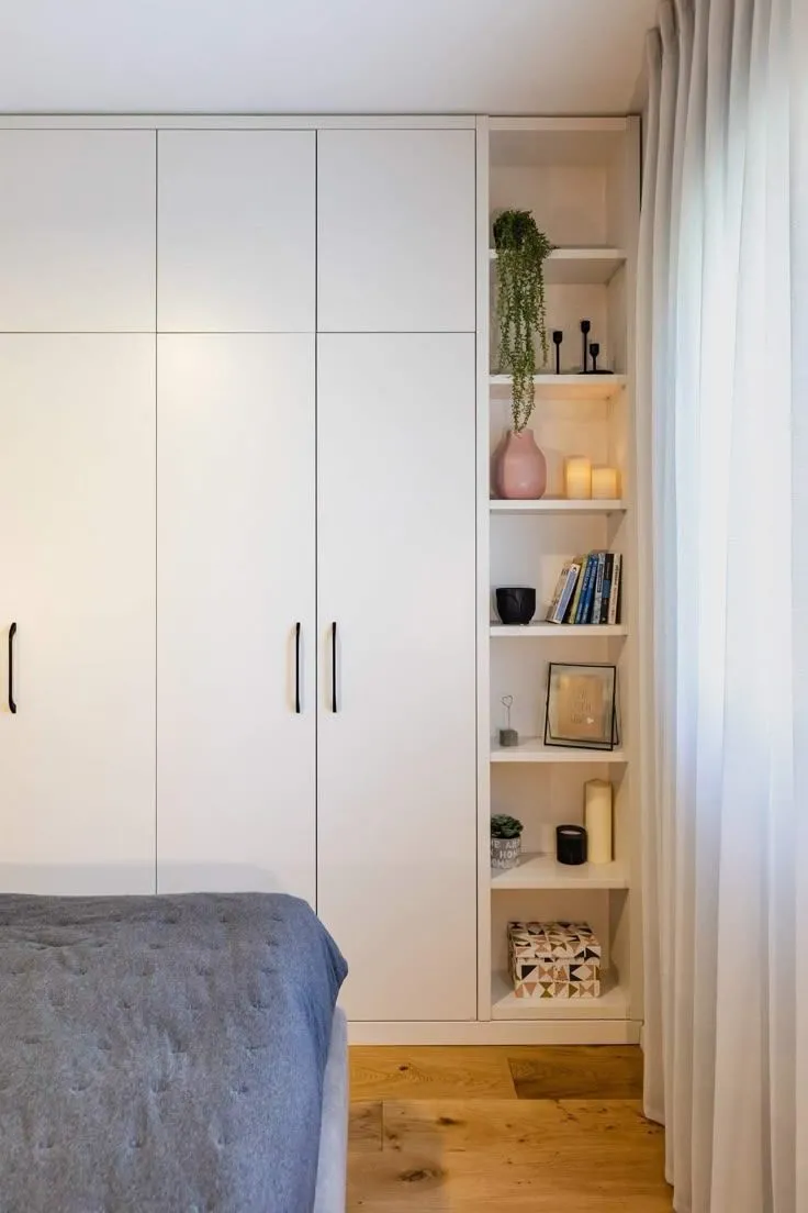 A sleek and elegant white wall almirah design with both open and cabinet storage shelves