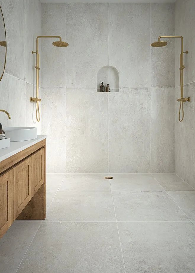 Large stone-textured white wall and floor tiles in a minimalist walk-in shower