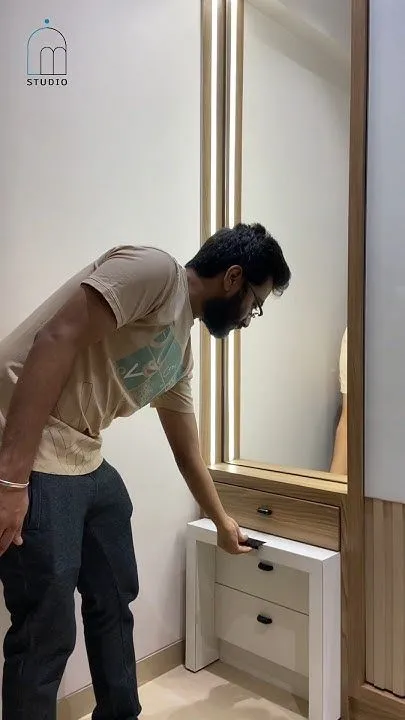 A person pulling out a concealed stool from a modern, minimalistic dressing table