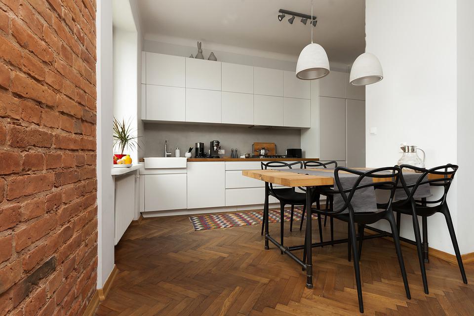 A pristine kitchen with white walls and a partial brick wall design