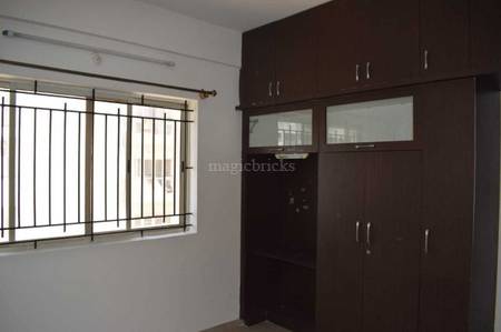 The room features a window, security grills, and wooden furniture at DSR Green Fields, Whitefield, Bangalore