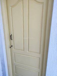 A creamcolored door with a black handle is against a wall