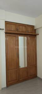 The wooden wardrobe with mirror complements the light-colored walls at Srinivasa Signature, Bellandur, Outer Ring Road, Bangalore